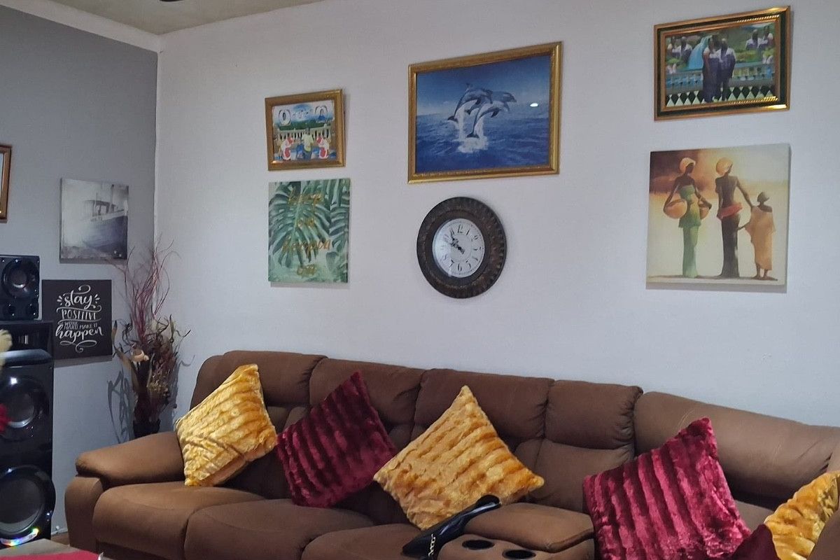 A comfortable living room space featuring a ceiling fan and neutral wall finishes, suitable for relaxation and family gatherings.