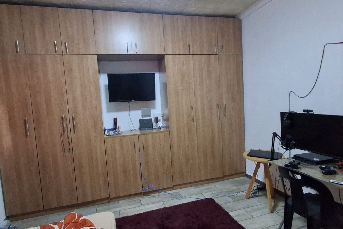 Bedroom featuring extensive floor-to-ceiling built-in wooden cabinetry with integrated shelving and tiled flooring.