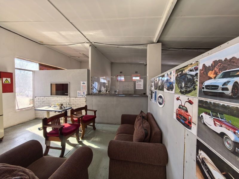 A commercial reception or waiting area featuring partition walls, a service counter, and basic industrial-style lighting.