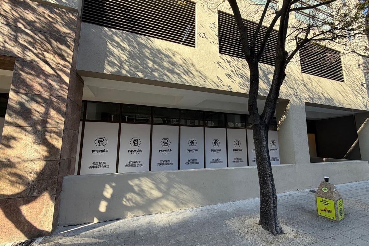 Street-level view of the retail property facade featuring large glass windows with branded privacy film and ventilation louvers above.