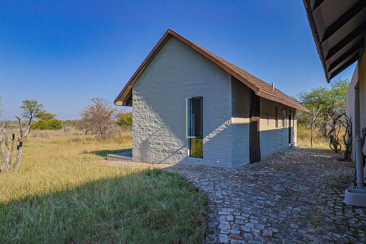 A view of the exterior rear of the farm building, featuring textured masonry walls, a pitched roof, and a paved stone walkway.