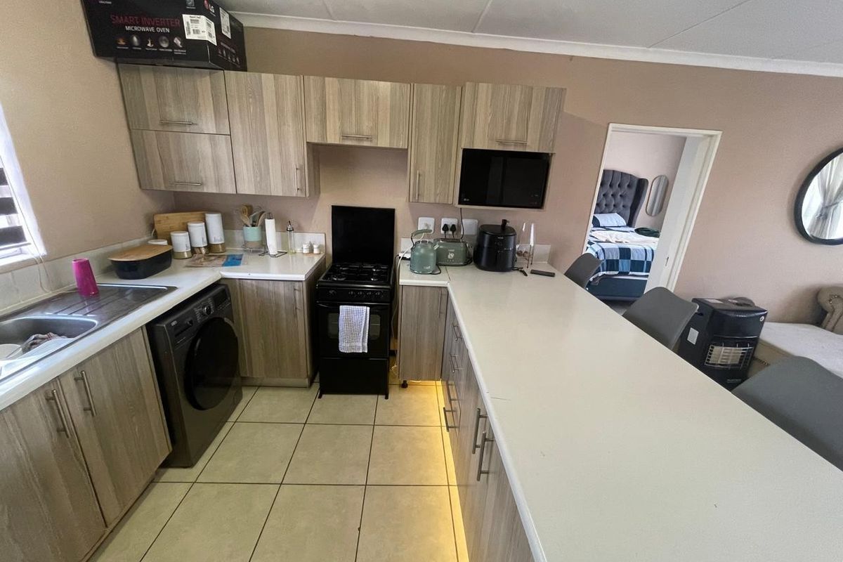 A functional kitchen featuring wood-look cabinetry, a breakfast bar, tiled flooring, and a built-in oven with hob.