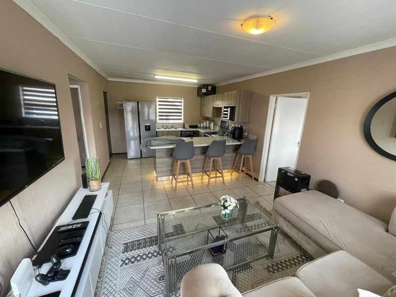 Open-plan living area featuring a kitchen with breakfast bar, tiled flooring, and neutral wall tones, creating a functional and connected living space.