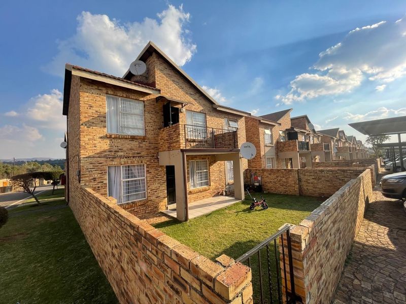 Exterior view of a multi-story apartment complex featuring face-brick facade, private ground-floor patio, balcony, and enclosed garden area.