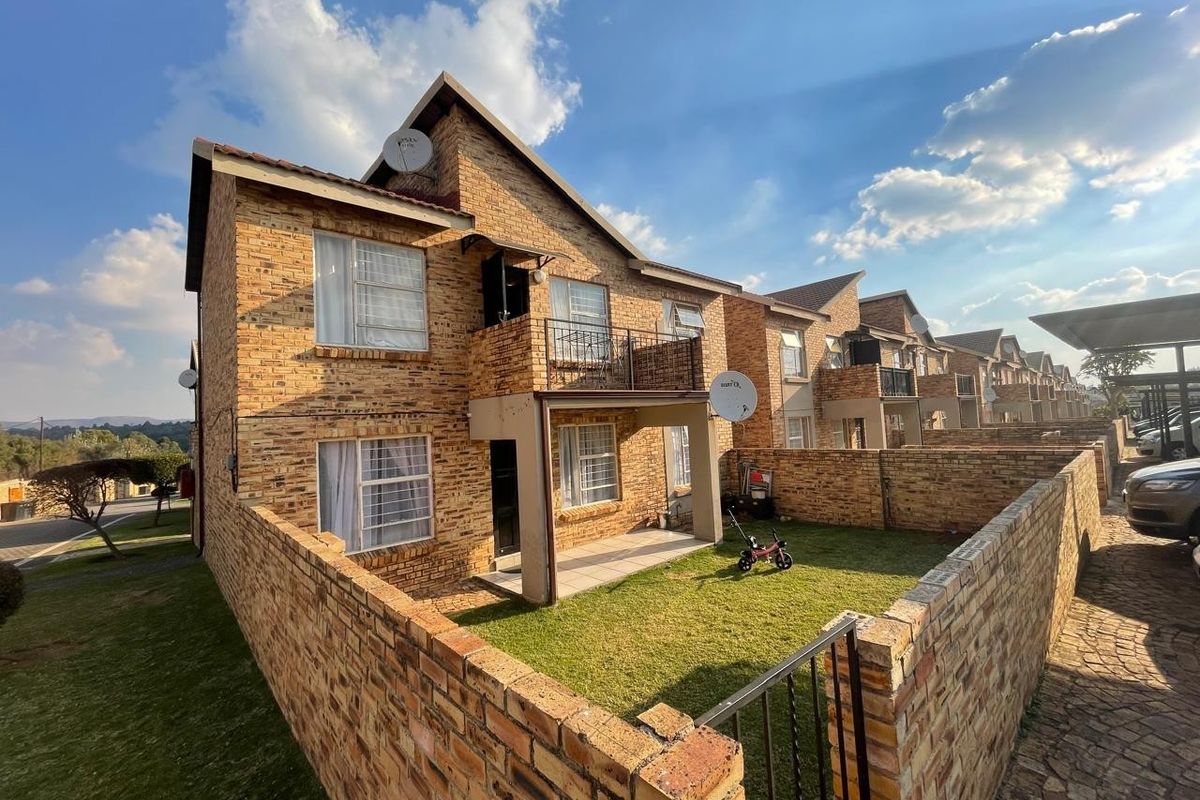 Exterior view of a multi-story apartment complex featuring face-brick facade, private ground-floor patio, balcony, and enclosed garden area.