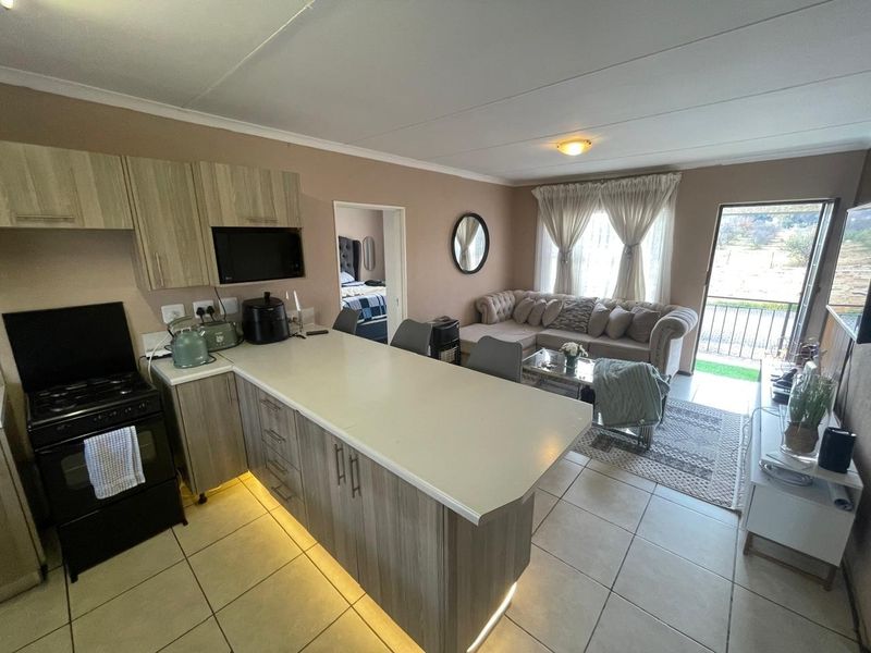 Open-plan living area featuring a modern kitchen with breakfast bar, tiled flooring, and direct access to a balcony.