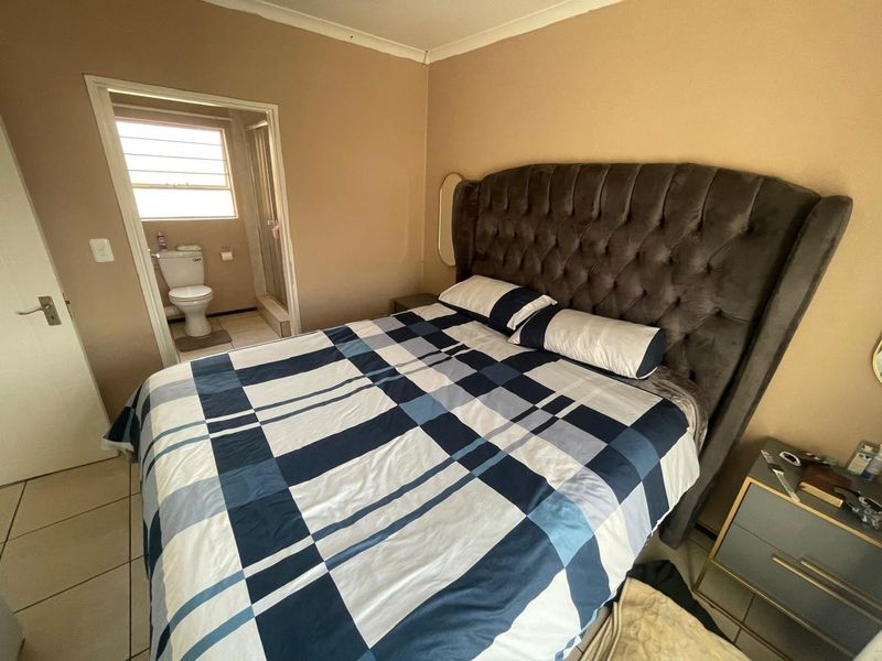 A bedroom featuring tiled flooring and an en-suite bathroom with a toilet and shower.