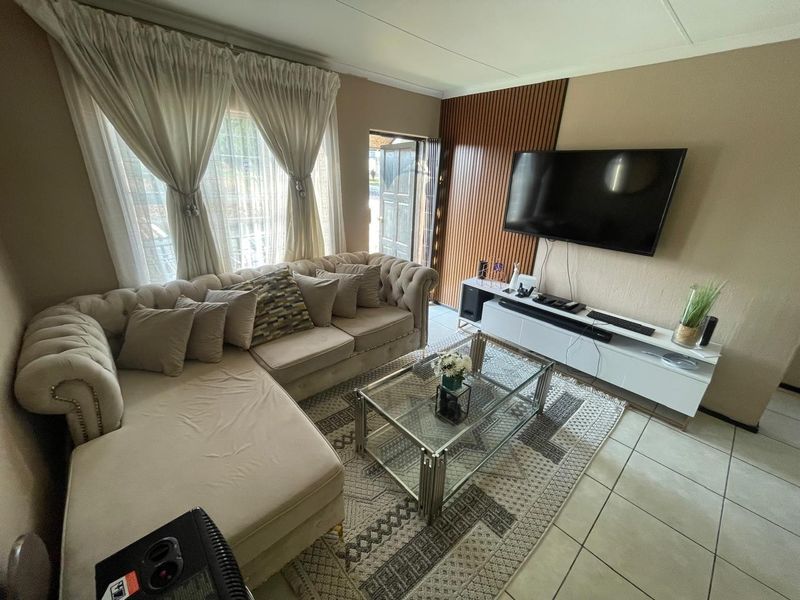 A comfortable living room featuring tiled flooring, a decorative timber-slat feature wall, and direct access to an exterior entrance.