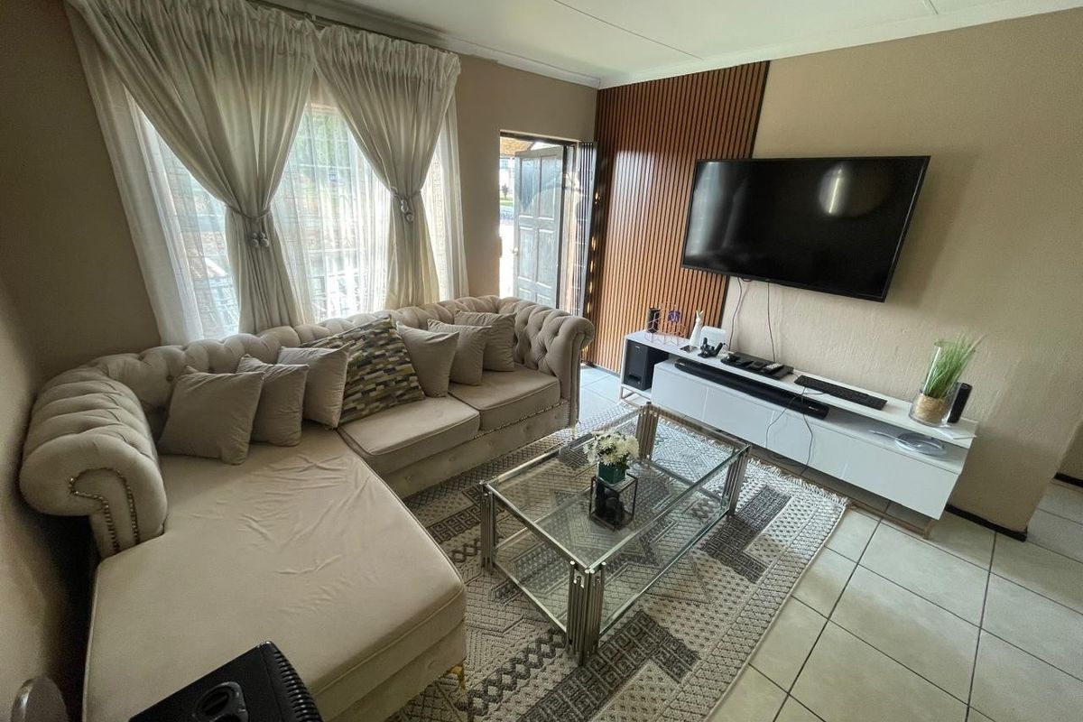 A comfortable living room featuring tiled flooring, a decorative timber-slat feature wall, and direct access to an exterior entrance.