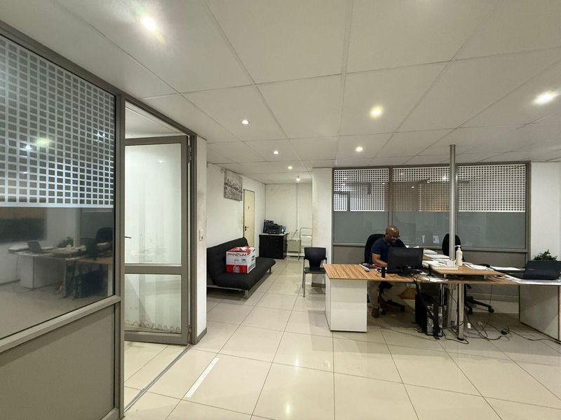 Functional office space featuring tiled flooring, suspended ceilings with recessed lighting, and aluminium-framed glass partitions for a professional industrial workspace environment.