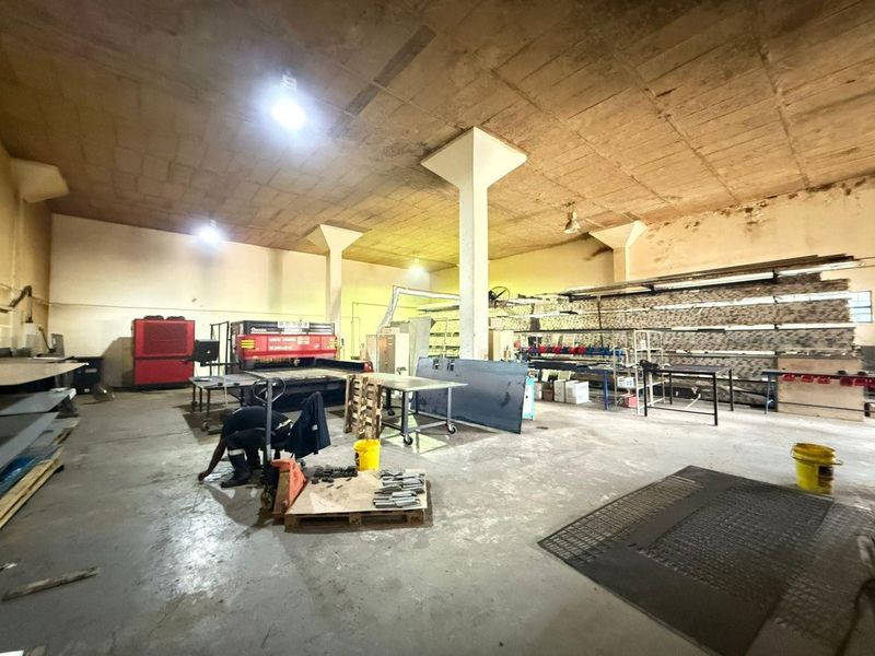 Spacious industrial utility area featuring high concrete ceilings, support columns, and durable concrete flooring, suitable for manufacturing or storage operations.