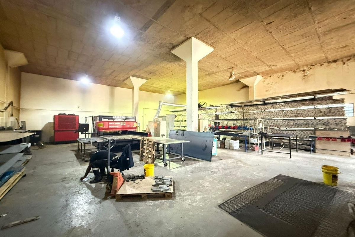 Spacious industrial utility area featuring high concrete ceilings, support columns, and durable concrete flooring, suitable for manufacturing or storage operations.