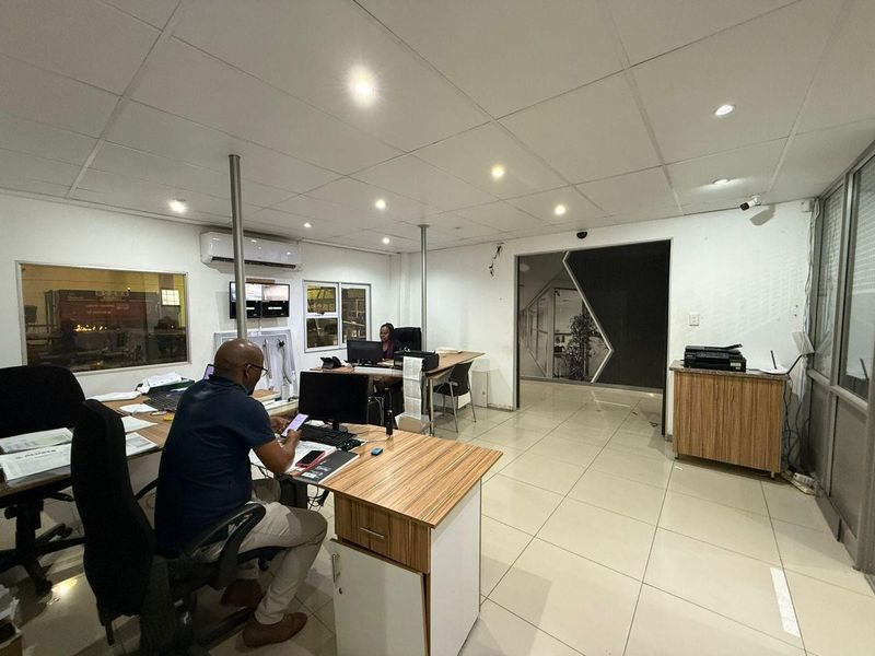 A functional industrial office space featuring tiled flooring, suspended ceilings with recessed lighting, and air conditioning, providing a practical work environment.