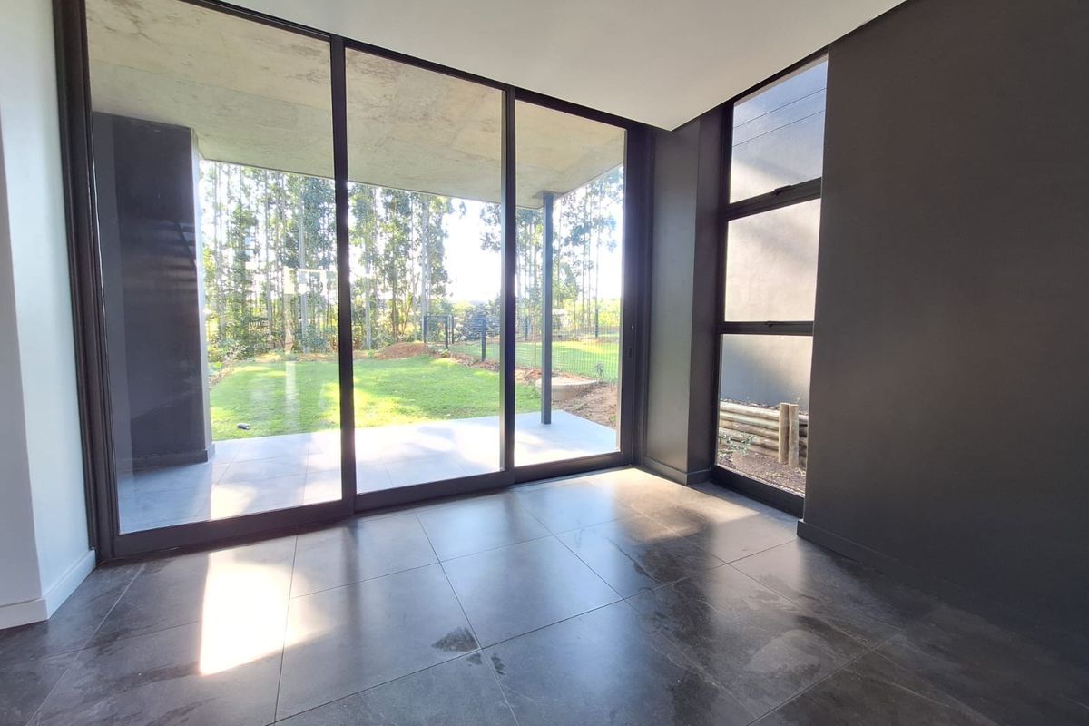 Modern living area featuring large floor-to-ceiling sliding glass doors that provide seamless access to the outdoor patio and garden.