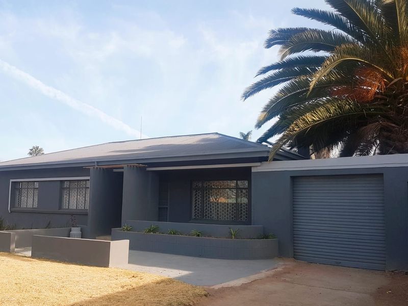 Front elevation of a modernised house featuring a grey facade, roller garage door, and integrated concrete planter boxes.