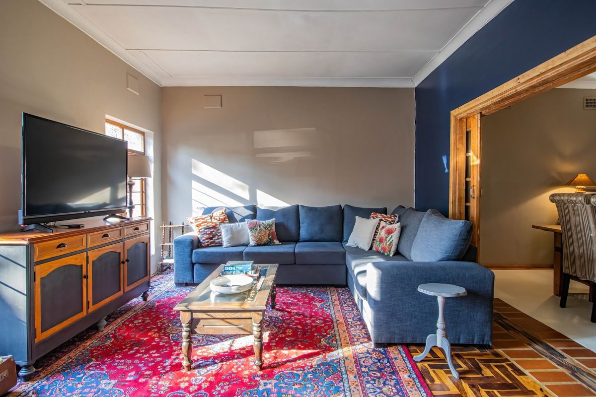 A cozy living room featuring parquet flooring, a dark blue accent wall, and a wooden sliding door leading to an adjacent space.