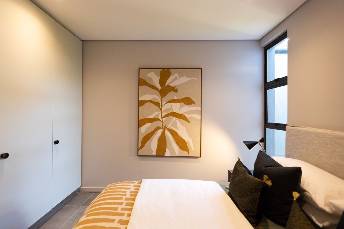 A modern bedroom featuring built-in floor-to-ceiling cabinetry, neutral wall finishes, and large windows providing natural light.