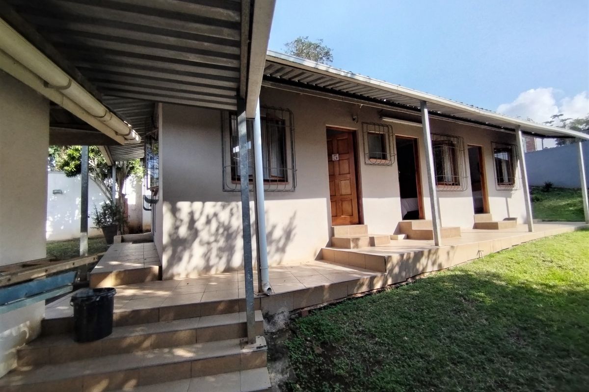 Exterior view of a lodge unit featuring a covered patio, tiled steps, and multiple entrance doors with security bars.
