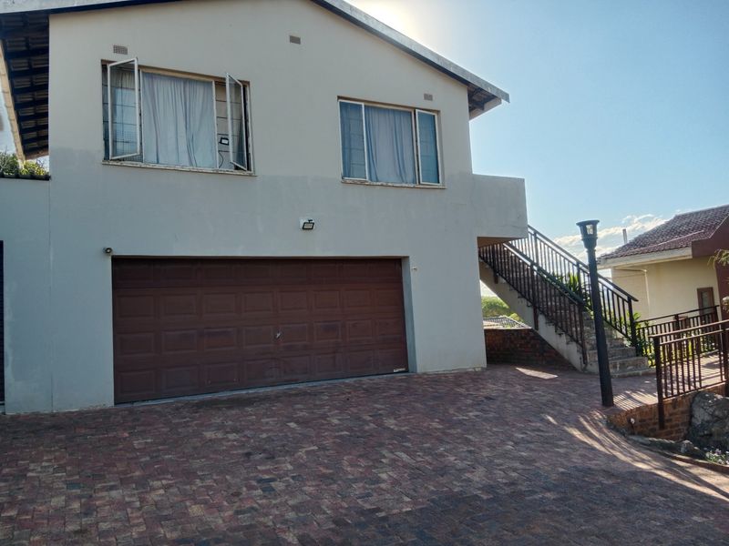 Front elevation of a two-story house featuring a double garage, paved driveway, and an external staircase leading to the upper level.