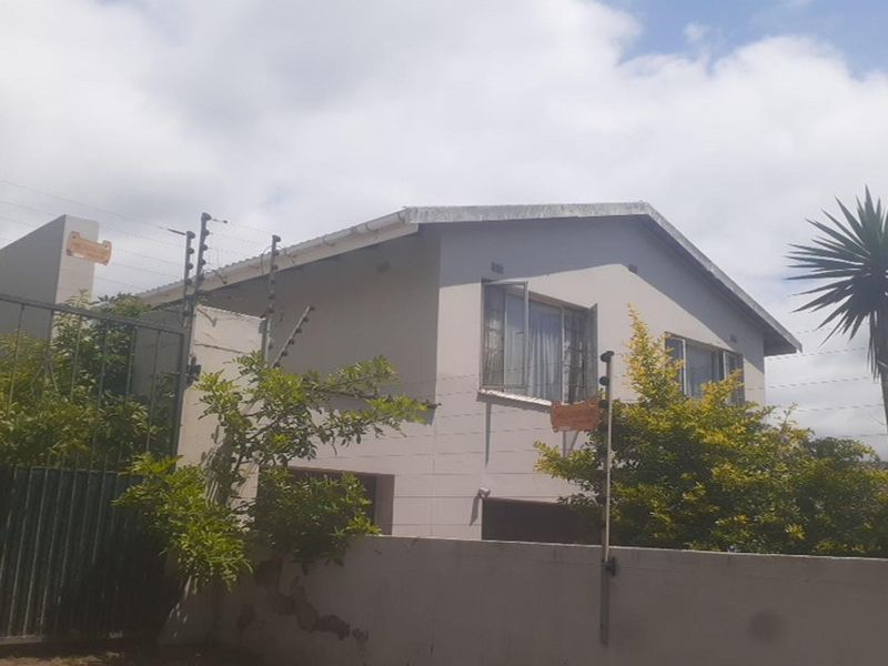 A view of the property exterior featuring a boundary wall, security fencing, and a multi-story residential building structure.