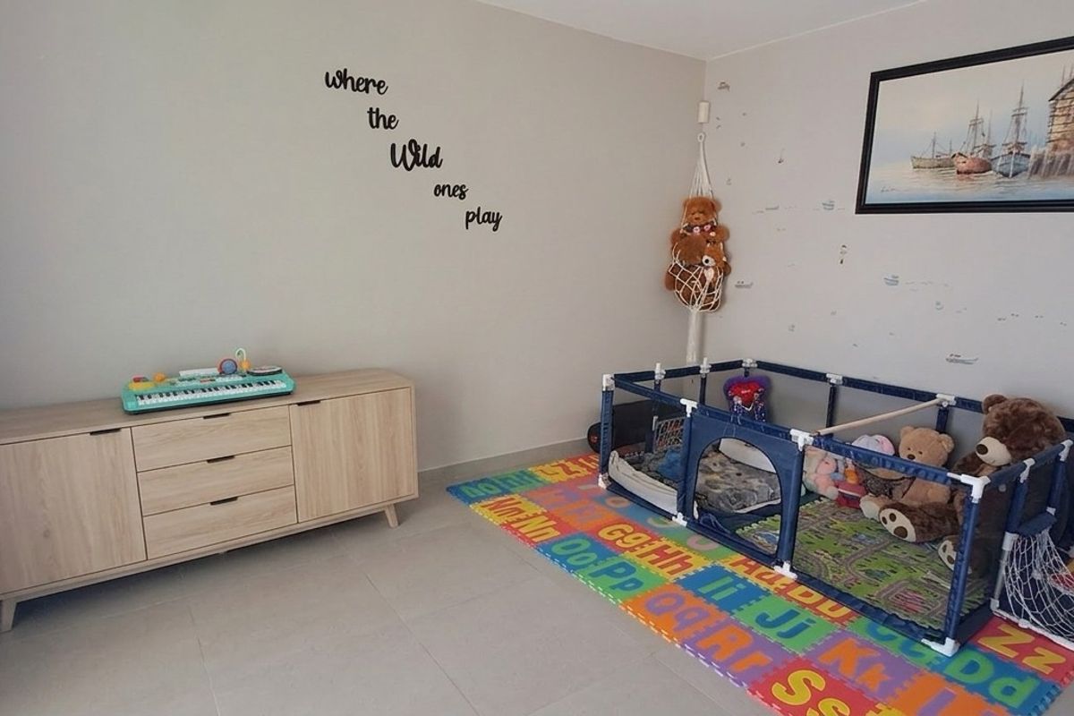 A bright bedroom featuring neutral wall tones and tiled flooring, currently utilized as a children's play and sleeping area.