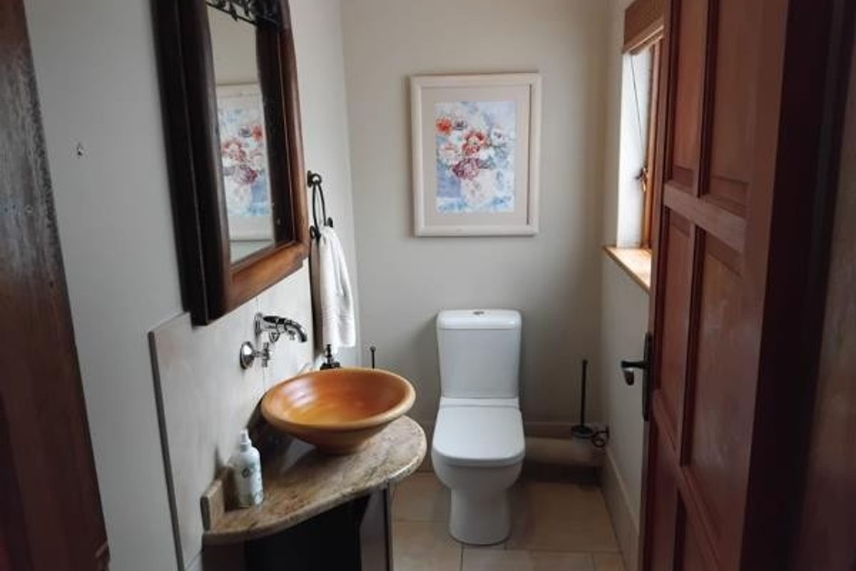 A compact guest bathroom featuring a vessel sink on a stone vanity top, a modern toilet, and wooden door frame.