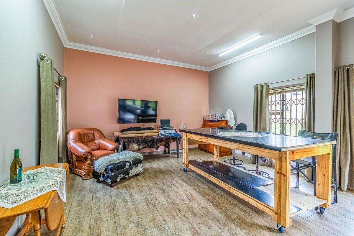 A versatile living space featuring wood-look tiled flooring, recessed ceiling lighting, and a prominent accent wall, suitable for use as a lounge or workspace.