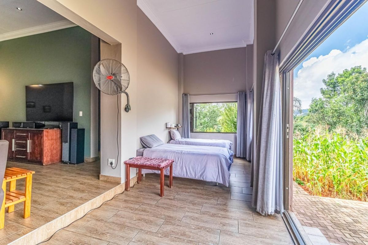 Spacious bedroom featuring tiled flooring, high ceilings, and large sliding glass doors providing direct access to the outdoor area.