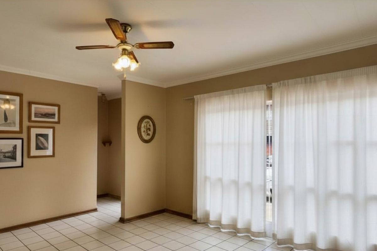 A living area featuring tiled flooring, a ceiling fan, and large sliding glass doors leading to an outdoor space.