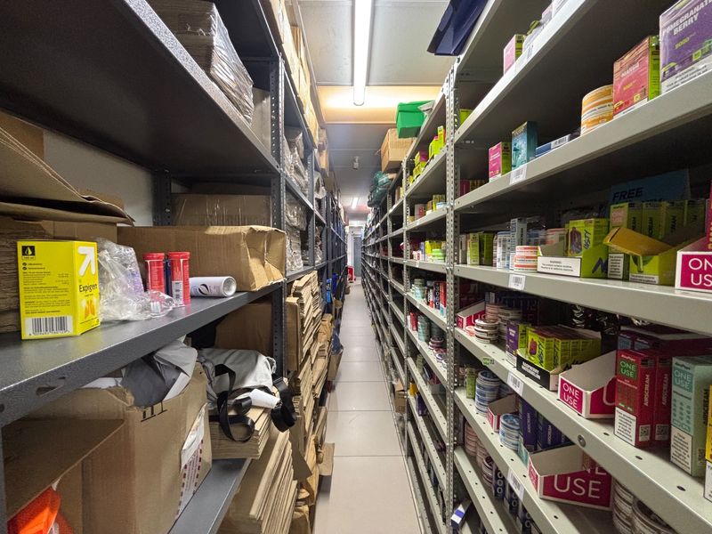 A functional utility storage area featuring extensive industrial metal shelving units and overhead fluorescent lighting, suitable for retail stock management.