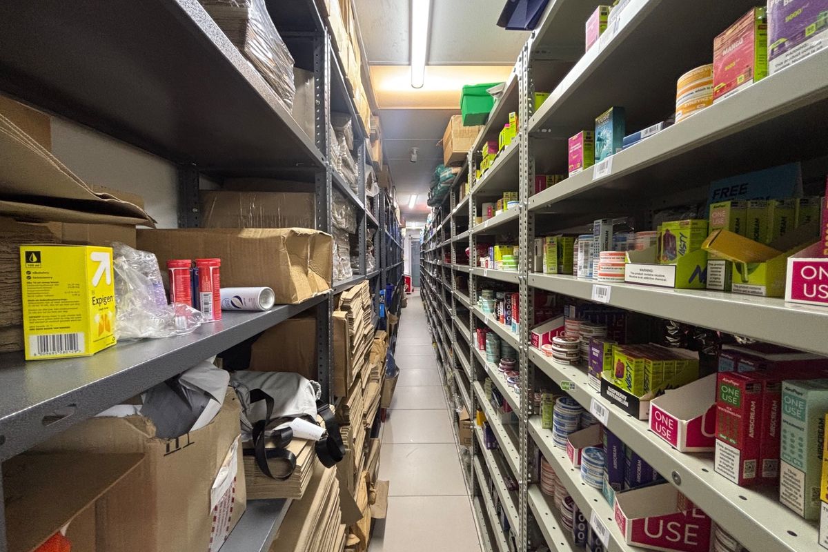 A functional utility storage area featuring extensive industrial metal shelving units and overhead fluorescent lighting, suitable for retail stock management.