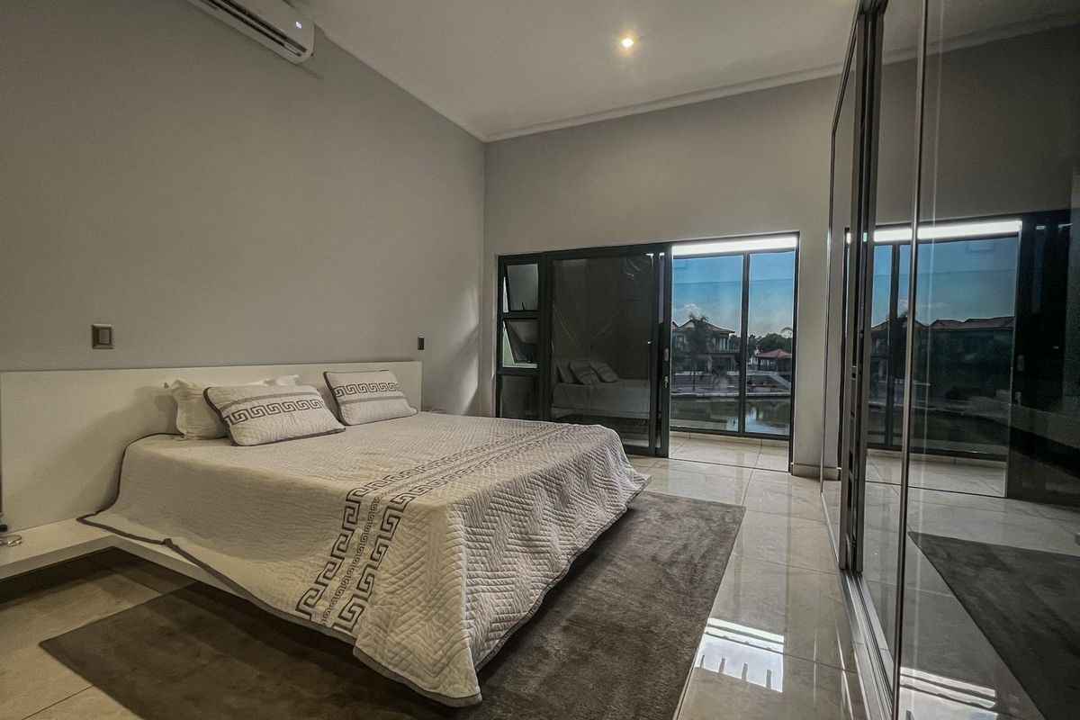 Spacious bedroom featuring large sliding glass doors, built-in mirrored wardrobes, recessed downlighting, and a wall-mounted air conditioning unit.