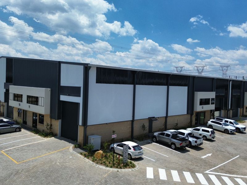 Aerial view of a modern industrial warehouse complex featuring corrugated metal cladding, roller shutter doors, and dedicated paved parking bays.