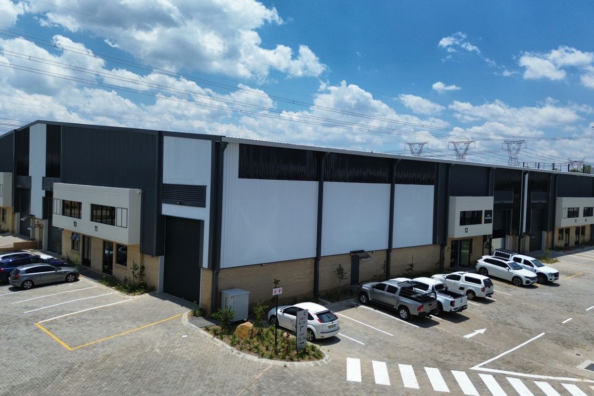 Aerial view of a modern industrial warehouse complex featuring corrugated metal cladding, roller shutter doors, and dedicated paved parking bays.