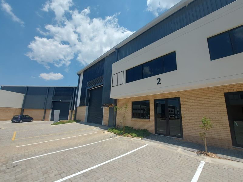 Modern industrial unit featuring a brick and metal facade, roller shutter door, and dedicated paved parking area.