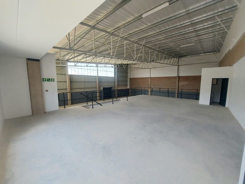 Spacious industrial utility area featuring exposed steel roof trusses, concrete flooring, and metal wall cladding, suitable for various commercial or storage applications.