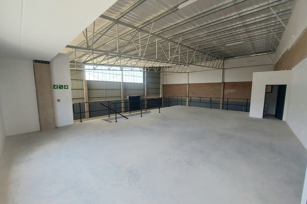 Spacious industrial utility area featuring exposed steel roof trusses, concrete flooring, and metal wall cladding, suitable for various commercial or storage applications.