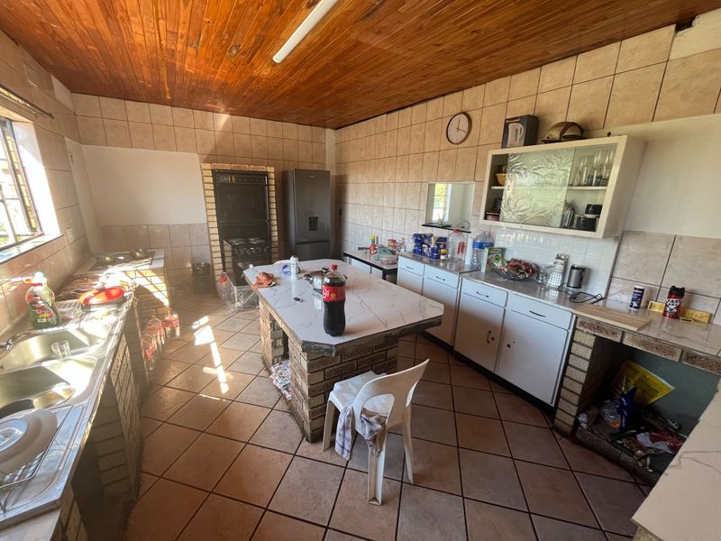 A dated kitchen featuring brick-based cabinetry, tiled walls, and a wooden ceiling, offering a functional layout with a central island and built-in oven.