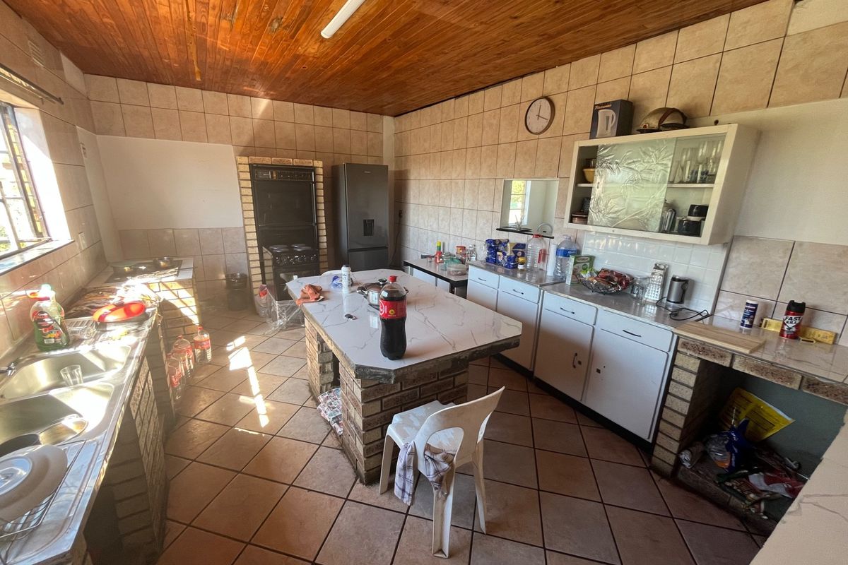 A dated kitchen featuring brick-based cabinetry, tiled walls, and a wooden ceiling, offering a functional layout with a central island and built-in oven.