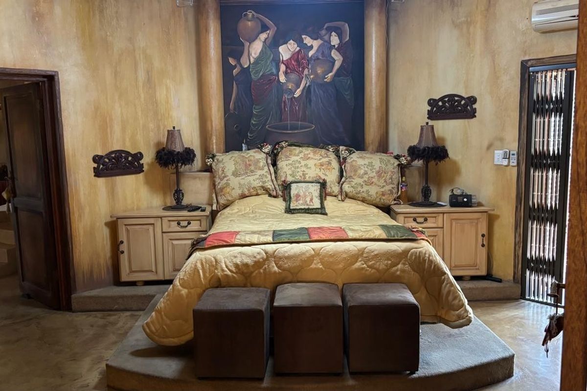 A bedroom featuring a raised platform bed area, textured wall finishes, and integrated bedside cabinetry.