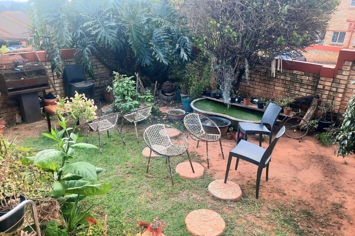A private rear garden area featuring a brick boundary wall, established trees, and a small water feature.