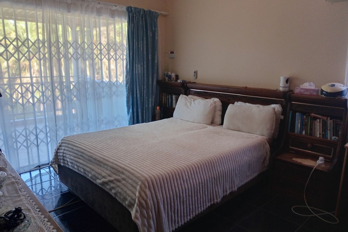 A bedroom featuring dark tiled flooring, a built-in headboard with integrated shelving, and sliding glass doors leading to an outdoor area.