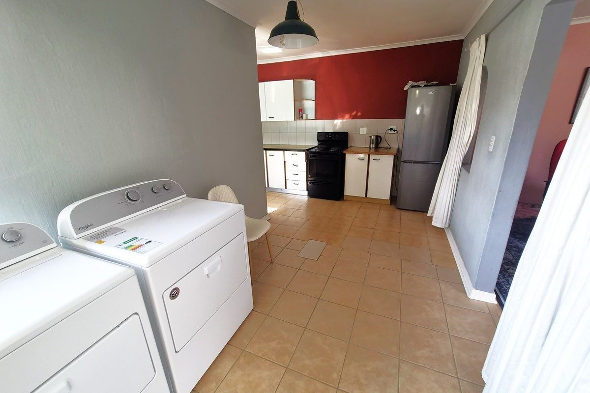 A functional kitchen and laundry area featuring tiled flooring, built-in cabinetry, and a freestanding stove, providing a practical space for daily household tasks.