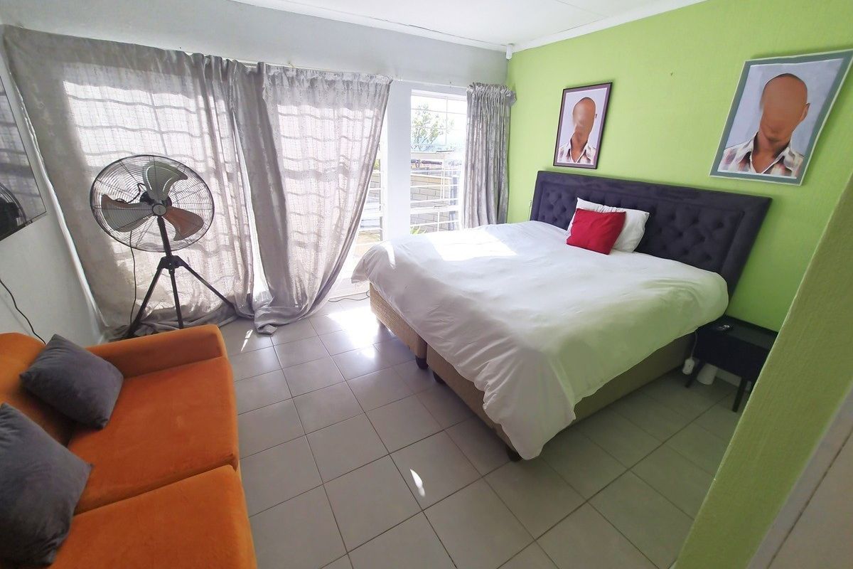 A bedroom featuring tiled flooring and large sliding glass doors that provide access to an outdoor area.