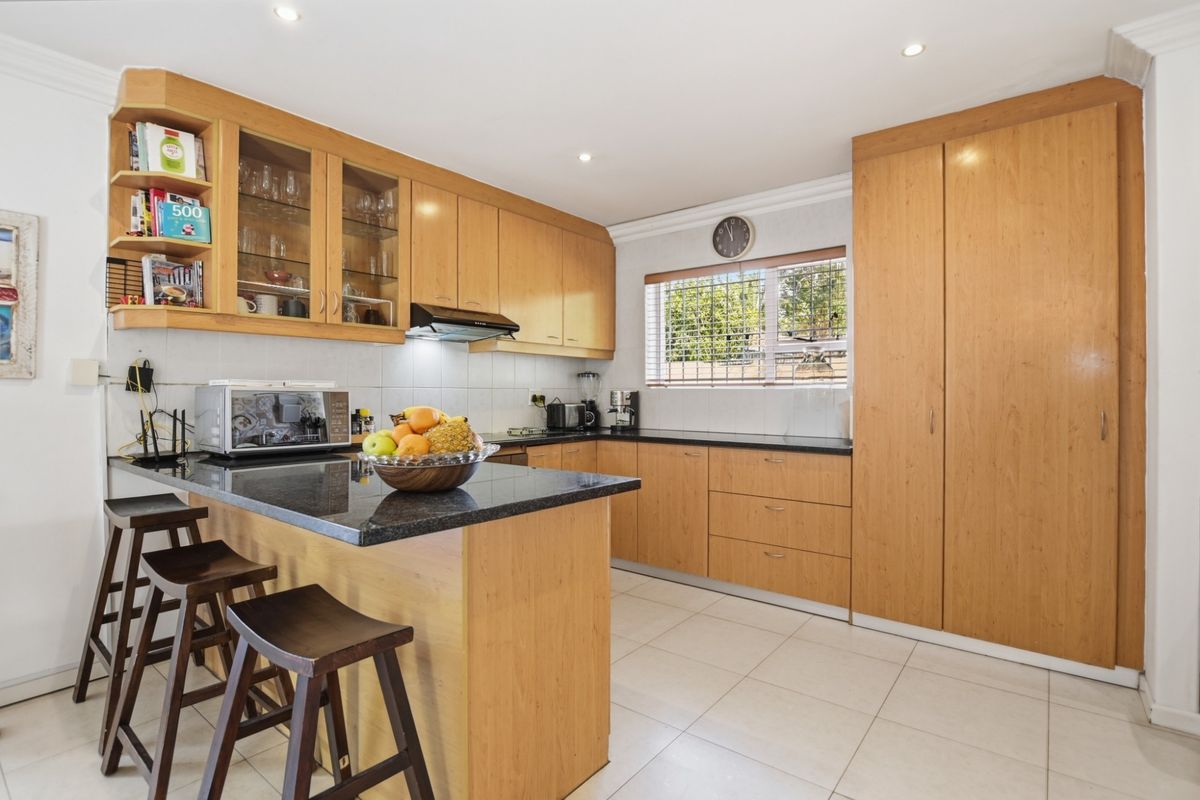A functional kitchen featuring light wood cabinetry, dark granite countertops, a breakfast bar, and integrated storage cupboards.