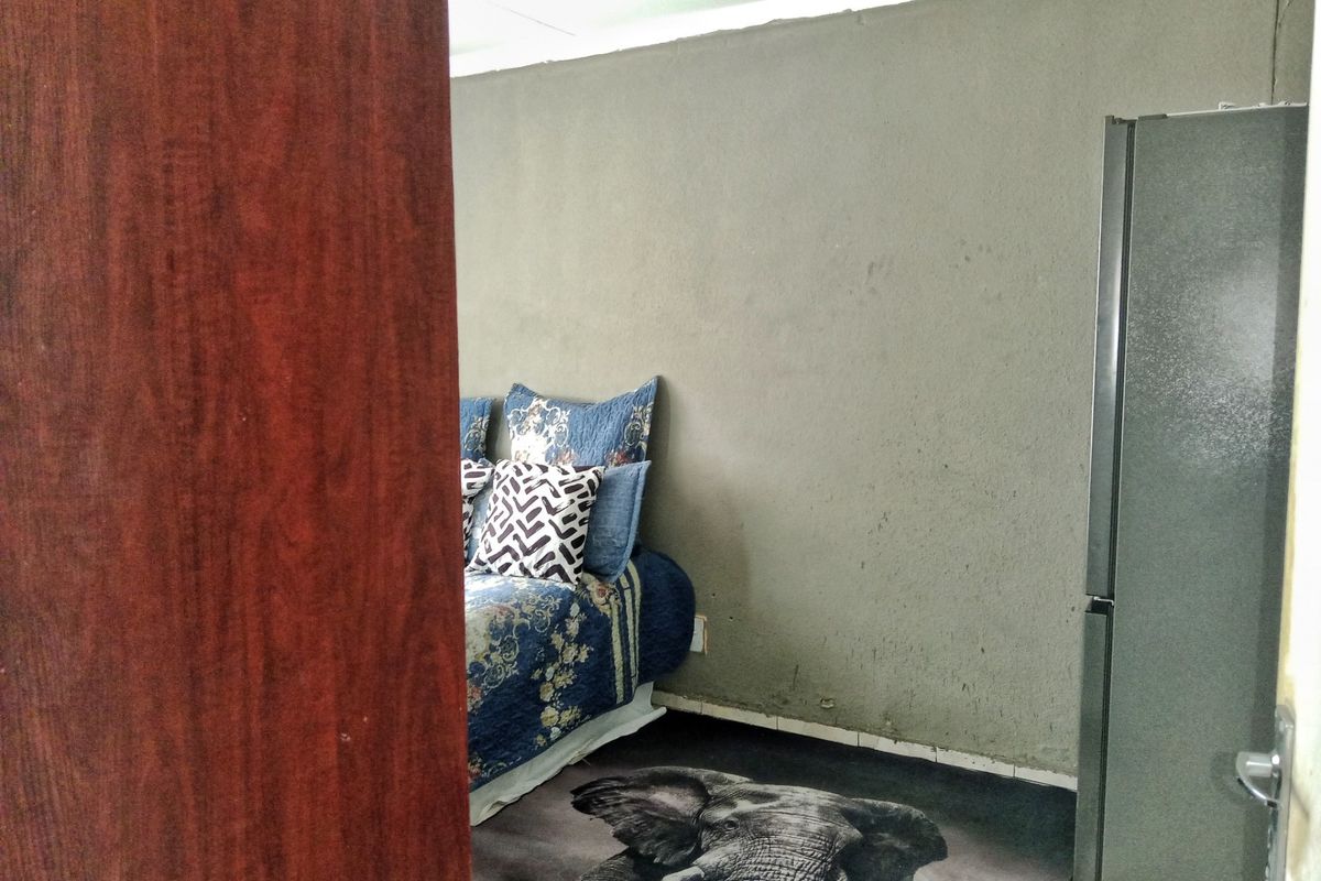 A bedroom interior featuring unfinished plastered walls and basic flooring, viewed through a doorway.