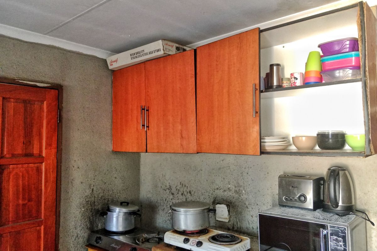 A kitchen area featuring wooden wall-mounted cabinetry and exposed, unfinished wall surfaces.