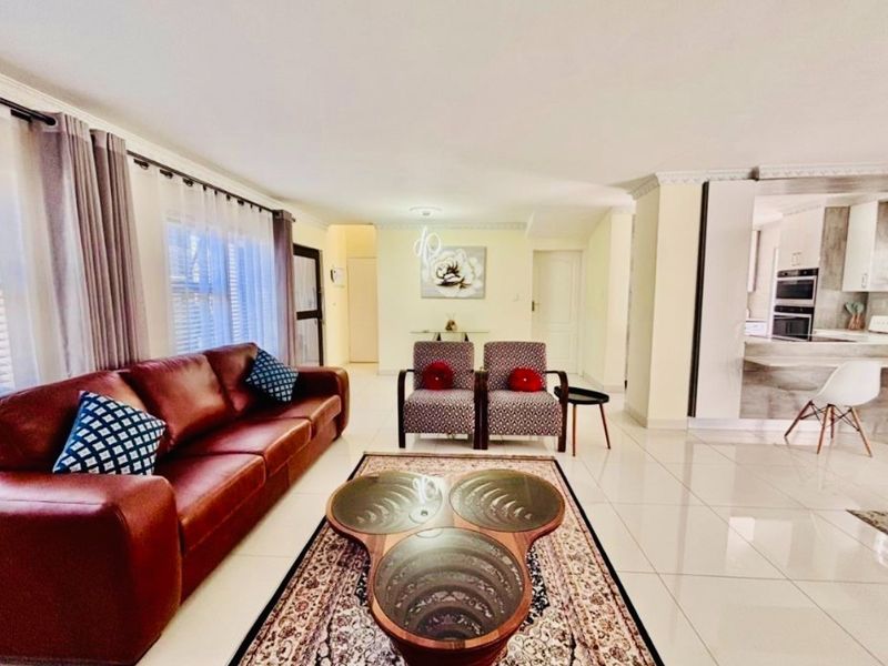 Spacious open-plan living area featuring polished floor tiles, crown molding, and a seamless transition into the modern kitchen with built-in oven.