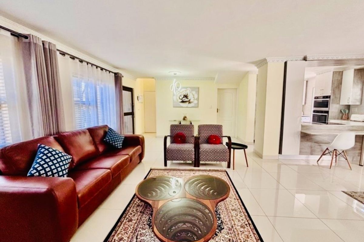 Spacious open-plan living area featuring polished floor tiles, crown molding, and a seamless transition into the modern kitchen with built-in oven.
