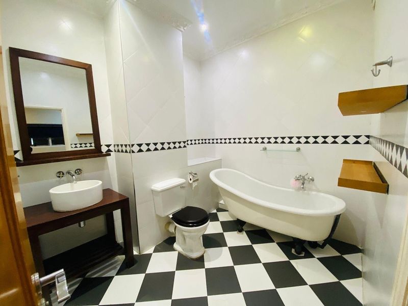 A well-maintained bathroom featuring a classic clawfoot bathtub, vessel sink vanity, and distinctive black and white checkered floor tiling.